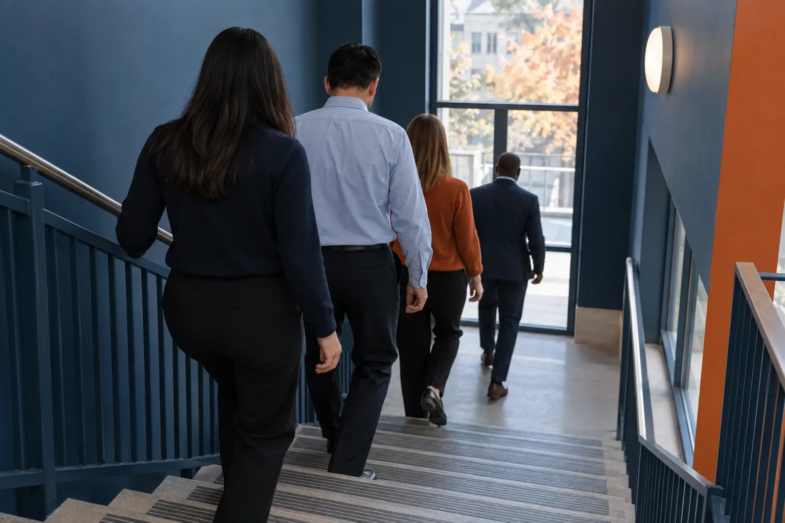 Salariés descendant calmement un escalier pendant un exercice d’évacuation, vus de dos.